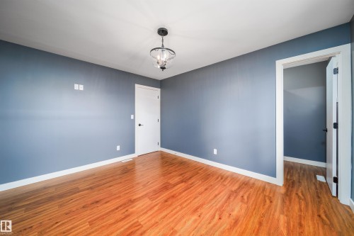 Spacious room featuring wood-finish flooring, light blue walls, and white trim - 126 Harrison Drive, Edmonton, AB - Indoor Photo Showing Other Room