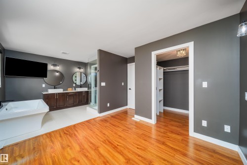 Open-concept room featuring wood-finish flooring, a freestanding soaking tub, and a dual-sink vanity with vessel sinks - 126 Harrison Drive, Edmonton, AB - Indoor
