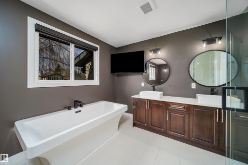 Modern bathroom featuring a freestanding soaking tub, a dual vanity with vessel sinks, dark wood cabinetry, and a glass-enclosed shower - 126 Harrison Drive, Edmonton, AB - Indoor Photo Showing Bathroom