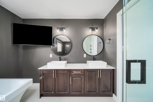 Dual vessel sinks set atop a dark wood-finish vanity with a light-colored countertop - 126 Harrison Drive, Edmonton, AB - Indoor