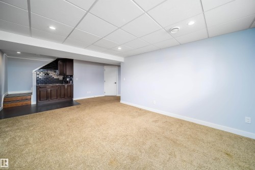 Spacious room featuring light blue walls and a drop ceiling with recessed lighting - 126 Harrison Drive, Edmonton, AB - Indoor
