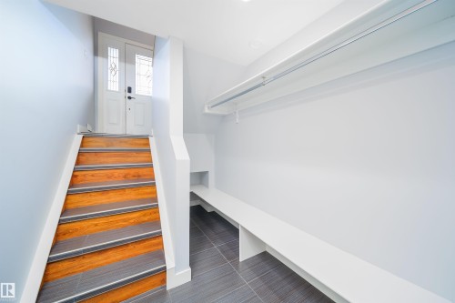 Entryway featuring a white double door with decorative glass inserts, wood-finish stairs with anti-slip treads, and a built-in storage bench with an overhead clothing rod - 126 Harrison Drive, Edmonton, AB - Indoor Photo Showing Other Room