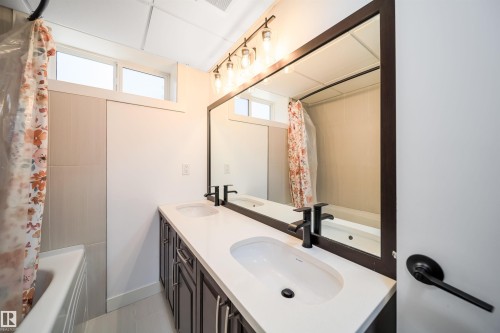 Dual vanity with white undermount sinks, matte black faucets, and a large wall-mounted mirror - 126 Harrison Drive, Edmonton, AB - Indoor Photo Showing Bathroom