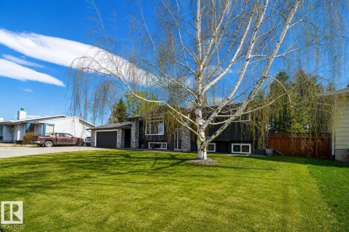 Front exterior featuring dark siding, stone accents, and a large front lawn - 126 Harrison Drive, Edmonton, AB - Outdoor