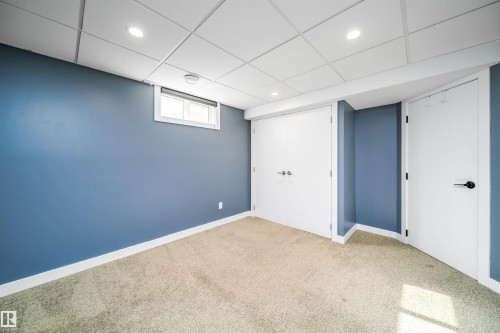 Carpeted room featuring a white grid ceiling with recessed lighting, blue painted walls, white trim, and a window - 126 Harrison Drive, Edmonton, AB - Indoor Photo Showing Other Room