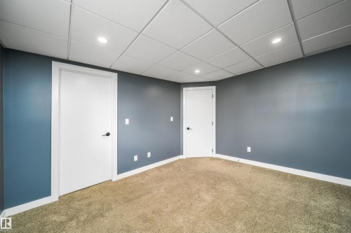 Room featuring plush carpeting, a grid ceiling with recessed lighting, and two white paneled doors with matte black hardware - 126 Harrison Drive, Edmonton, AB - Indoor Photo Showing Other Room
