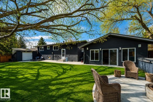 Expansive rear yard featuring a concrete patio, lush lawn, and mature trees - 126 Harrison Drive, Edmonton, AB - Outdoor