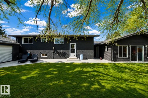 Spacious backyard with a large concrete patio, expansive lawn, and mature trees providing natural shade - 126 Harrison Drive, Edmonton, AB - Outdoor