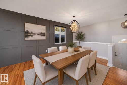 Dining area featuring a wainscoting accent wall, wood-finish flooring, and a contemporary chandelier - 126 Harrison Drive, Edmonton, AB - Indoor Photo Showing Dining Room