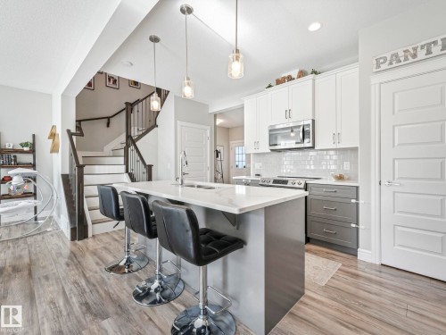 Kitchen featuring a central island with countertop seating, stainless steel appliances, white subway tile backsplash, and wood-finish flooring - 3817 Robins Crescent, Edmonton, AB - Indoor Photo Showing Kitchen With Upgraded Kitchen