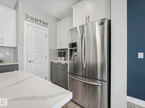 Kitchen featuring a large stainless steel refrigerator, white and gray cabinetry, light gray subway tile backsplash, and a white countertop with subtle veining - 3817 Robins Crescent, Edmonton, AB - Indoor Photo Showing Kitchen With Stainless Steel Kitchen