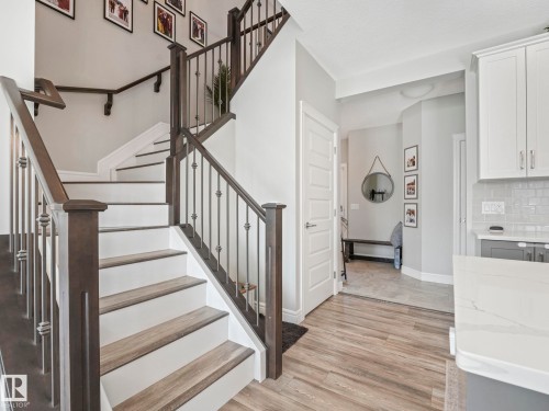 Staircase featuring wood-finish treads, white risers, and dark wood newel posts with iron balusters - 3817 Robins Crescent, Edmonton, AB - Indoor Photo Showing Other Room