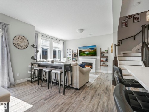 Living area featuring wood-finish flooring, a white fireplace with a mantel, and multiple windows with blinds - 3817 Robins Crescent, Edmonton, AB - Indoor With Fireplace