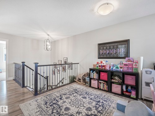Upper landing featuring wood-finish flooring, a metal spindle railing, and a contemporary flush-mount ceiling light - 3817 Robins Crescent, Edmonton, AB - Indoor Photo Showing Other Room