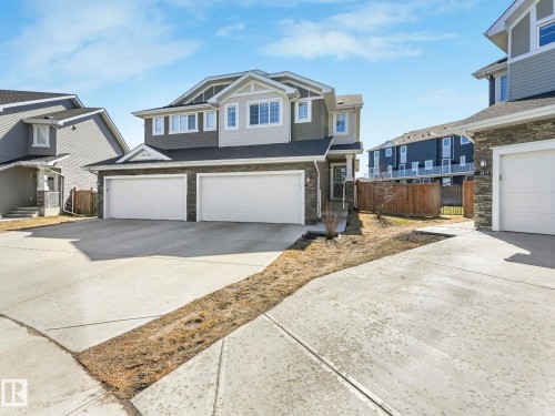 Multi-level residential exterior featuring a two-car garage, stone veneer accents, light siding, and a concrete driveway - 3817 Robins Crescent, Edmonton, AB - Outdoor With Facade