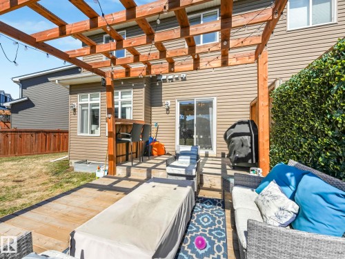 Expansive outdoor living area featuring a multi-level wood deck, a prominent wood pergola with integrated string lights, and a sliding glass door for interior access - 3817 Robins Crescent, Edmonton, AB - Outdoor