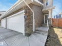 Exterior featuring a two-car garage with white doors, stone facade accents, horizontal siding, a covered entryway with a white column, and concrete steps - 3817 Robins Crescent, Edmonton, AB  - Outdoor 