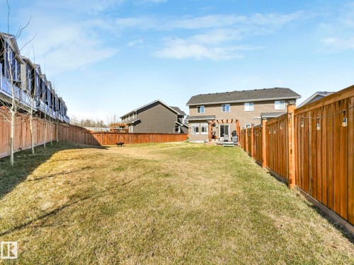 Expansive backyard featuring a spacious lawn, wood privacy fencing, and a rear deck with a pergola - 3817 Robins Crescent, Edmonton, AB - Outdoor