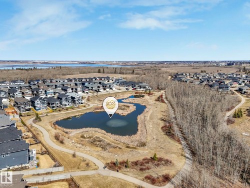 Aerial perspective showcasing a residential development with a central pond feature - 3817 Robins Crescent, Edmonton, AB - Outdoor With View