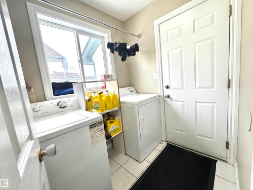 Laundry area with independent washer and dryer, light tile patterned flooring, and a textured ceiling - 6734 162A Avenue, Edmonton, AB - Indoor Photo Showing Laundry Room