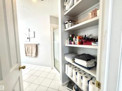 Bathroom with a textured ceiling, a shower stall, and light tile patterned floors - 