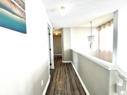 Corridor with a textured ceiling, hanging lights, and dark wood-type flooring - 