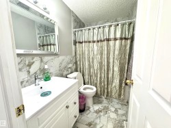 Bathroom featuring light marble finish flooring, vanity, a shower with shower curtain, a textured ceiling, and tile walls - 