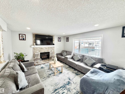 Living area featuring a stone fireplace, a textured ceiling, and recessed lighting - 6734 162A Avenue, Edmonton, AB - Indoor Photo Showing Living Room With Fireplace