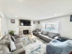 Living area featuring a stone fireplace, a textured ceiling, and recessed lighting - 