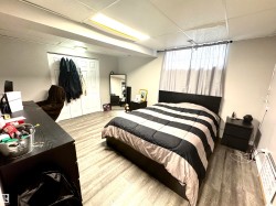 Bedroom with a closet, a paneled ceiling, light wood-style flooring, and an office area - 