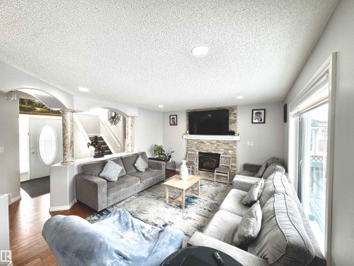 Living room featuring arched walkways, a textured ceiling, recessed lighting, wood-type flooring, and a fireplace - 6734 162A Avenue, Edmonton, AB - Indoor Photo Showing Living Room With Fireplace