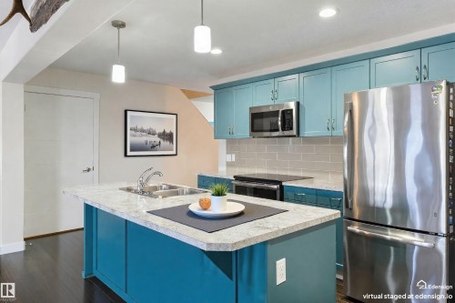 Kitchen featuring teal cabinetry, stainless steel appliances, a light-colored countertop, and recessed lighting - 4914 47 Street, Redwater, AB - Indoor Photo Showing Kitchen With Double Sink