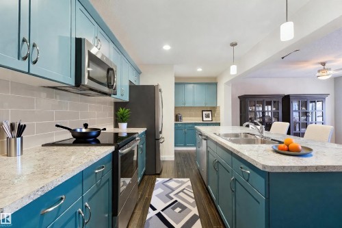 Virtually stagged Kitchen is featuring two-tone cabinetry, stainless steel appliances, a large island with dual sinks, and wood-finish flooring - 4914 47 Street, Redwater, AB - Indoor Photo Showing Kitchen With Double Sink With Upgraded Kitchen