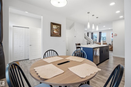 The dining area features wood-look flooring and a contemporary round overhead light fixture - 4047 Hawthorn Link Link, Edmonton, AB - Indoor Photo Showing Dining Room