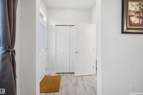 Entryway featuring light-colored wood-look flooring, a white front door with an opaque glass insert, and a white interior door - 4047 Hawthorn Link Link, Edmonton, AB - Indoor Photo Showing Other Room