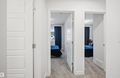Interior hallway with light gray carpeting and white paneled doors - 4047 Hawthorn Link Link, Edmonton, AB - Indoor Photo Showing Other Room