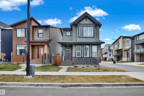 The property features a two-story exterior with siding and stone accents, a dark gray front door, and a partially fenced yard - 4047 Hawthorn Link Link, Edmonton, AB - Outdoor With Facade