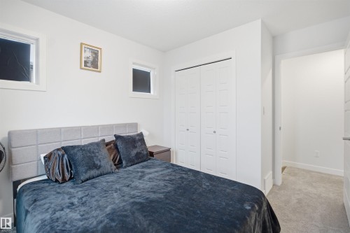 This room features neutral-toned walls, a light gray upholstered headboard, and two windows - 4047 Hawthorn Link Link, Edmonton, AB - Indoor Photo Showing Bedroom
