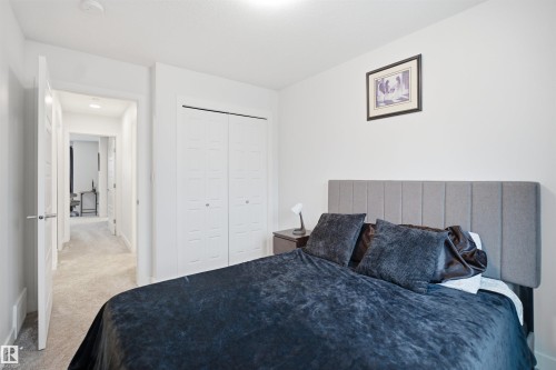 This room features light-colored walls and carpeted flooring, with a closet showcasing bi-fold doors - 4047 Hawthorn Link Link, Edmonton, AB - Indoor Photo Showing Bedroom