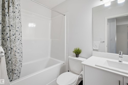 Well-appointed bathroom featuring a clean white bathtub and shower combination, a modern vanity with a white countertop and integrated sink, a sleek chrome faucet, and an illuminated mirror - 4047 Hawthorn Link Link, Edmonton, AB - Indoor Photo Showing Bathroom