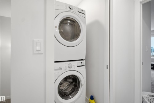 Laundry area featuring a stacked washer and dryer, set within a white-painted alcove - 4047 Hawthorn Link Link, Edmonton, AB - Indoor Photo Showing Laundry Room