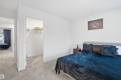 Bedroom with light gray carpeting, white walls, and a gray upholstered headboard - 4047 Hawthorn Link Link, Edmonton, AB - Indoor Photo Showing Bedroom