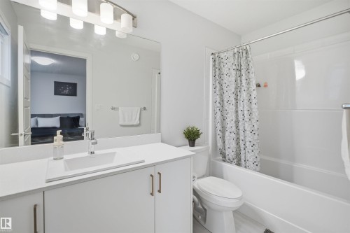 The bathroom features a vanity with a white countertop and an undermount sink, a toilet, and a bathtub with a shower - 4047 Hawthorn Link Link, Edmonton, AB - Indoor Photo Showing Bathroom