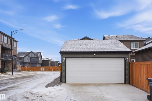 Detached single garage with a white garage door, dark green siding, and a snow-dusted roof - 4047 Hawthorn Link Link, Edmonton, AB - Outdoor With Exterior
