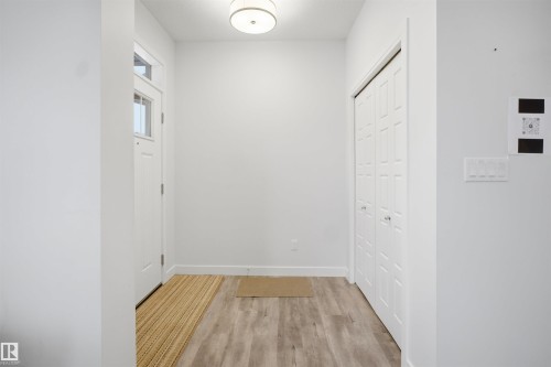 The entry features a front door with a window, light-toned flooring, and a closet with bifold doors - 4047 Hawthorn Link Link, Edmonton, AB - Indoor Photo Showing Other Room