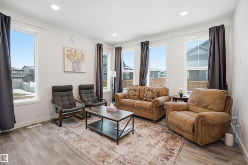 Living area featuring light grey wood flooring, multiple windows providing natural light, and recessed lighting - 4047 Hawthorn Link Link, Edmonton, AB - Indoor Photo Showing Living Room