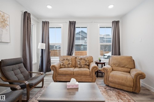 Living room featuring light-colored walls, recessed lighting, and windows with dark curtains - 4047 Hawthorn Link Link, Edmonton, AB - Indoor Photo Showing Living Room