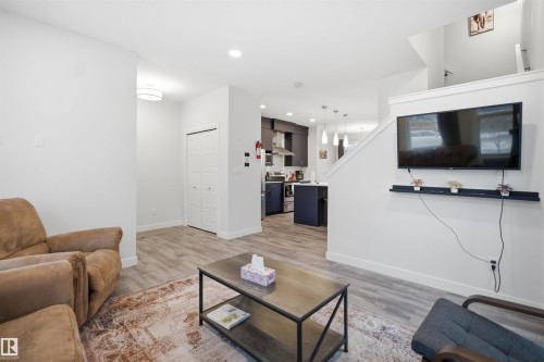 Open concept living area featuring light-colored flooring and white walls, with a view into the kitchen - 4047 Hawthorn Link Link, Edmonton, AB - Indoor Photo Showing Living Room