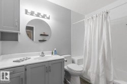 Bathroom featuring a single vanity with gray cabinetry, white countertop, and integrated sink - 