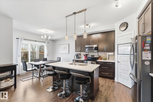 Modern kitchen featuring dark wood cabinetry, stainless steel appliances, and light countertops - 54 Cypress Link, Fort Saskatchewan, AB - Indoor Photo Showing Kitchen With Upgraded Kitchen